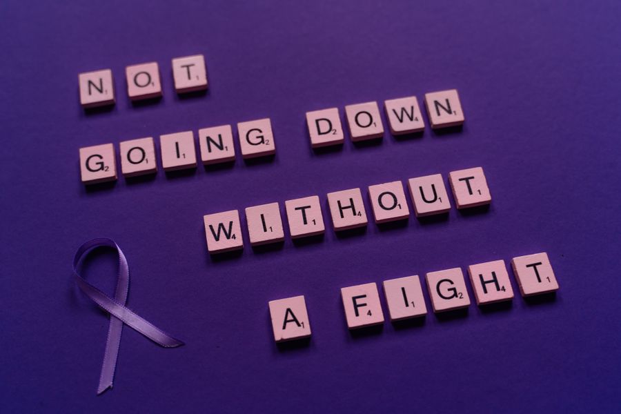 Purple epilepsy awareness ribbon on a purple background with the words 'Not going down without a fight' — epilepsy advocacy